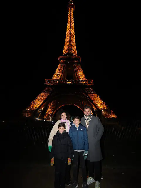 Renato com a família diante da Torre Eiffel iluminada
