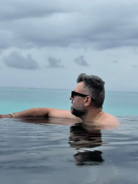 Renato numa piscina de borda infinita, de frente para o mar, nas Maldivas